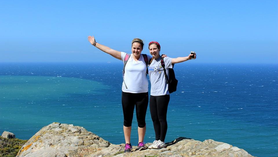 两个学生站在俯瞰大海的山顶上